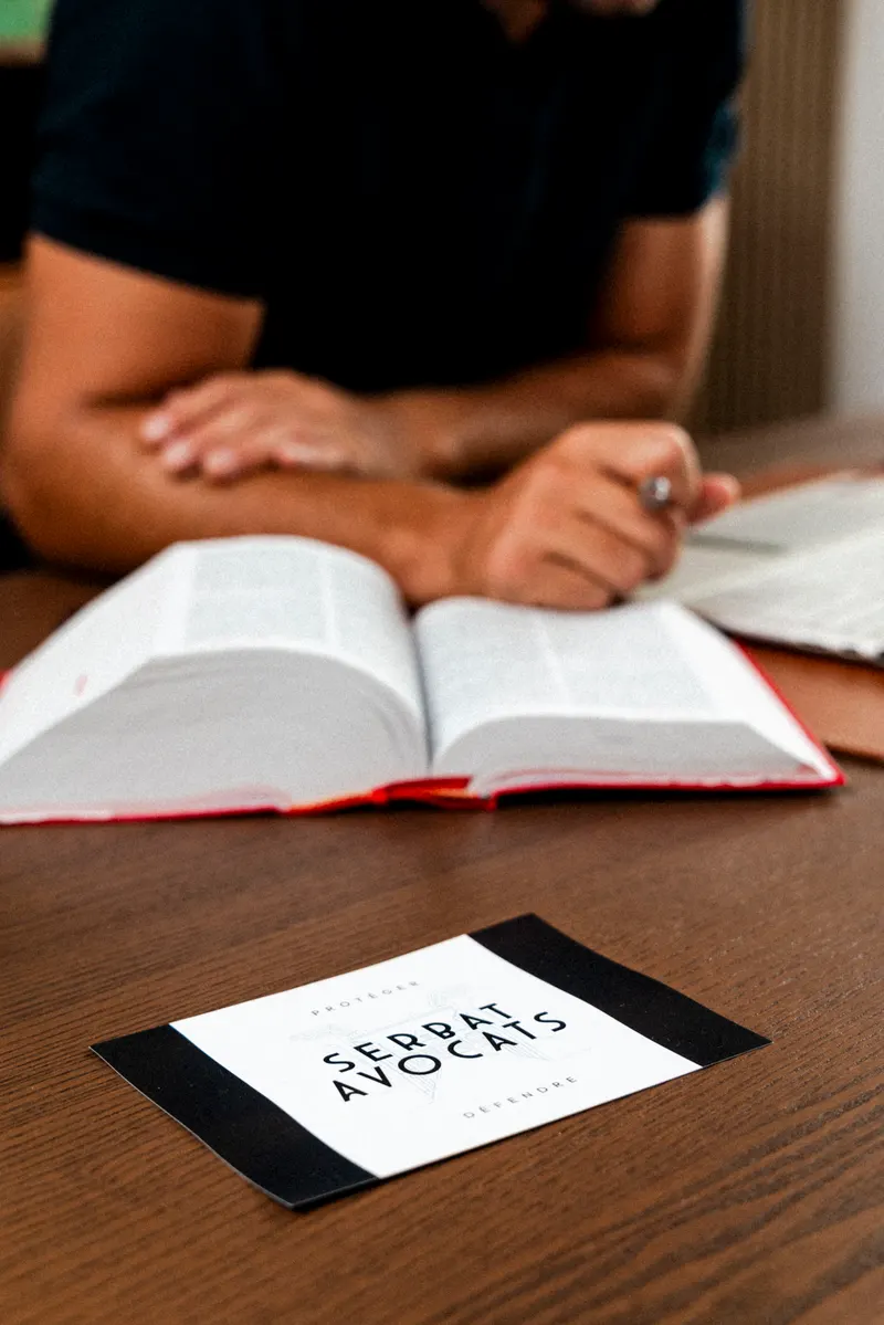 Carte de visite Serbat Avocats posée sur le bureau, devant des codes juridiques ouverts