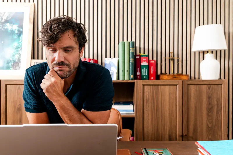 Maître Clément Lazies, pensif face à son ordinateur, devant une bibliothèque de codes juridiques